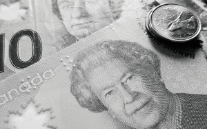 Close-up of a Canadian ten-dollar bill with Queen Elizabeth II’s portrait and stacked coins, highlighting Canadian currency details