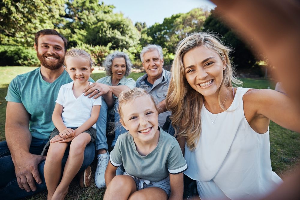 Happy multi-generational Canadian family taking a selfie together in a sunny park during summer
