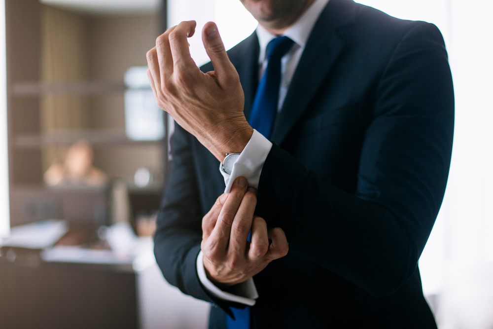 Man adjusting suit cuff and watch before first day at new job—ready thanks to a fast Loan Express work-wardrobe loan