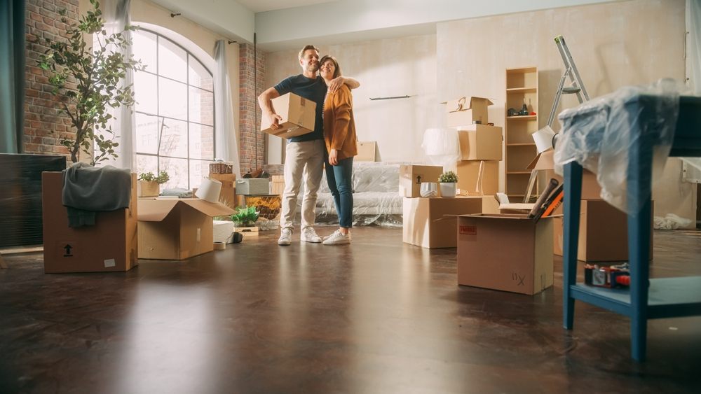 Couple standing in their new apartment surrounded by moving boxes after covering last-minute moving costs with a payday loan in Canada