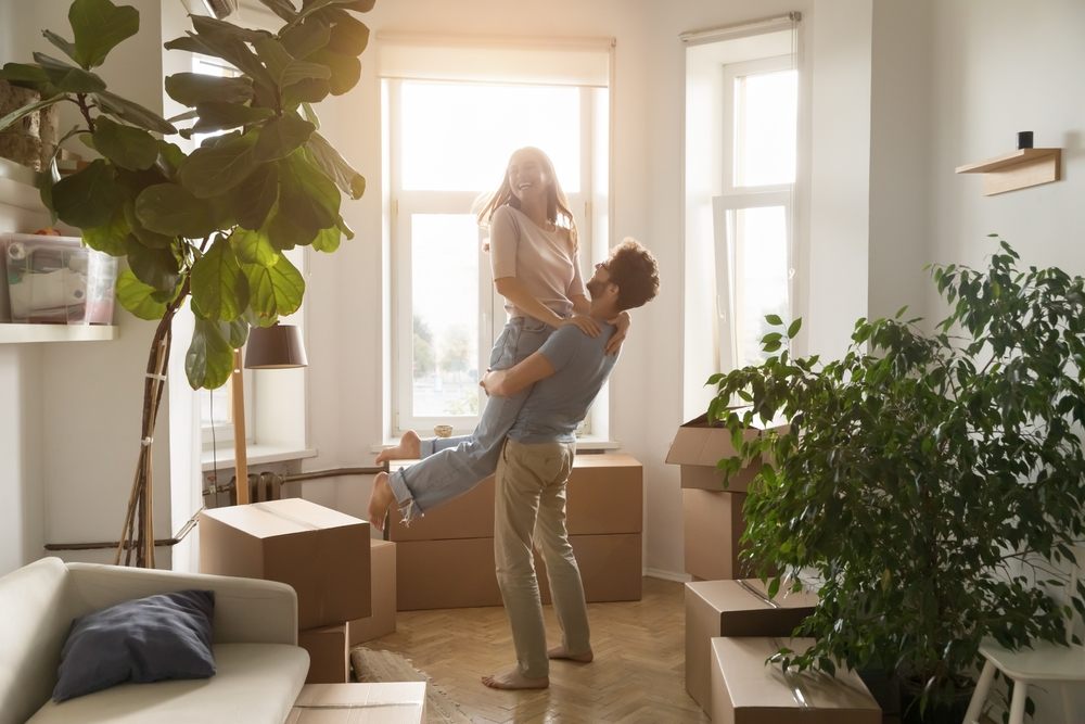 Happy couple celebrating in new apartment surrounded by moving boxes after securing a rent deposit loan in Canada