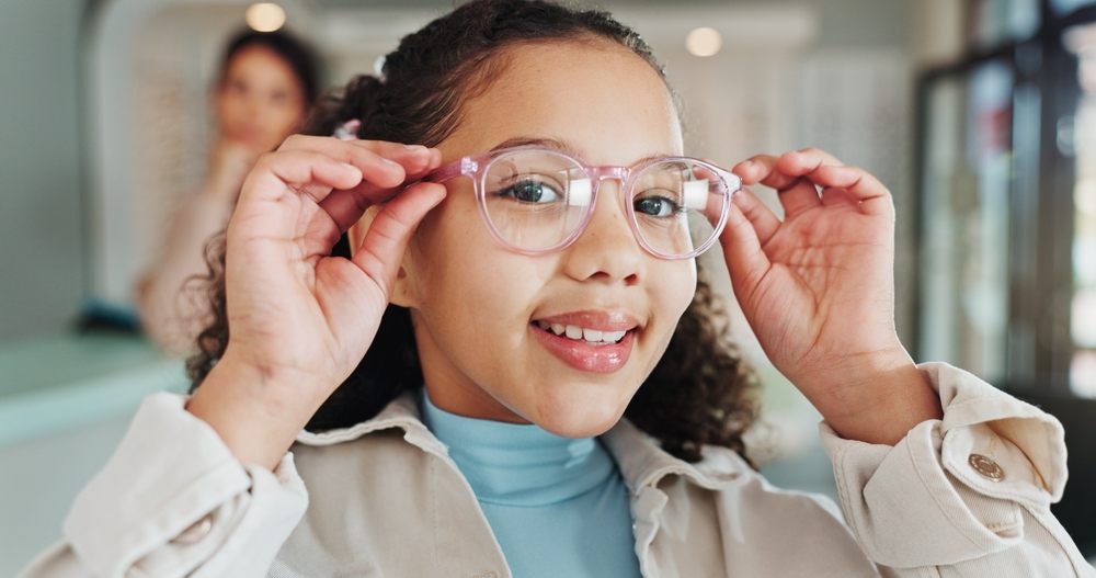 Smiling girl trying on new eyeglasses at optometrist after receiving a vision care loan in Canada