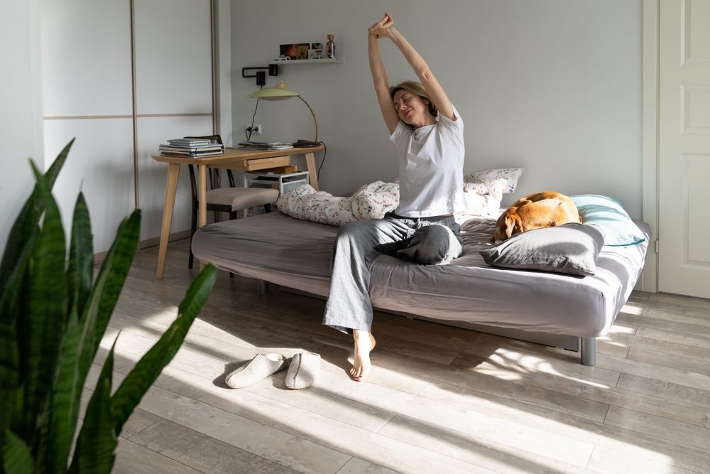 Relieved woman stretching in her apartment after securing rent arrears loan and resolving back rent