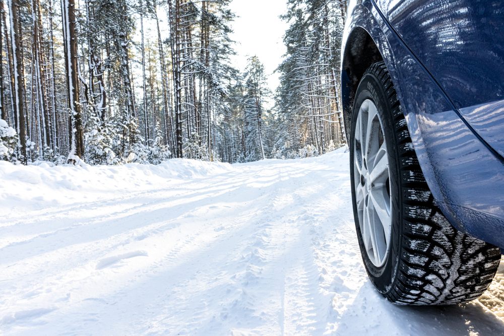 Vehicle with winter tires driving safely on snowy winter road through forest