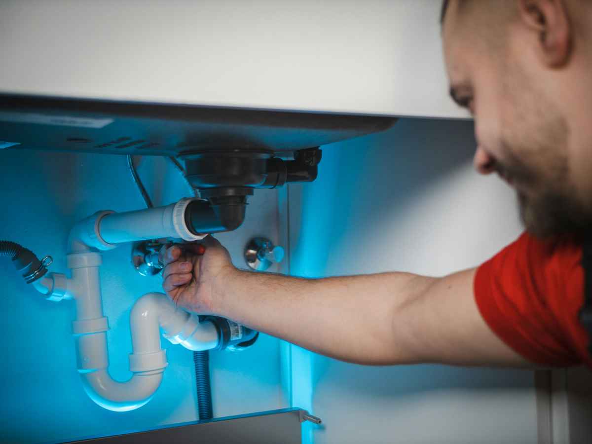 A plumber inspecting pipes under a sink.