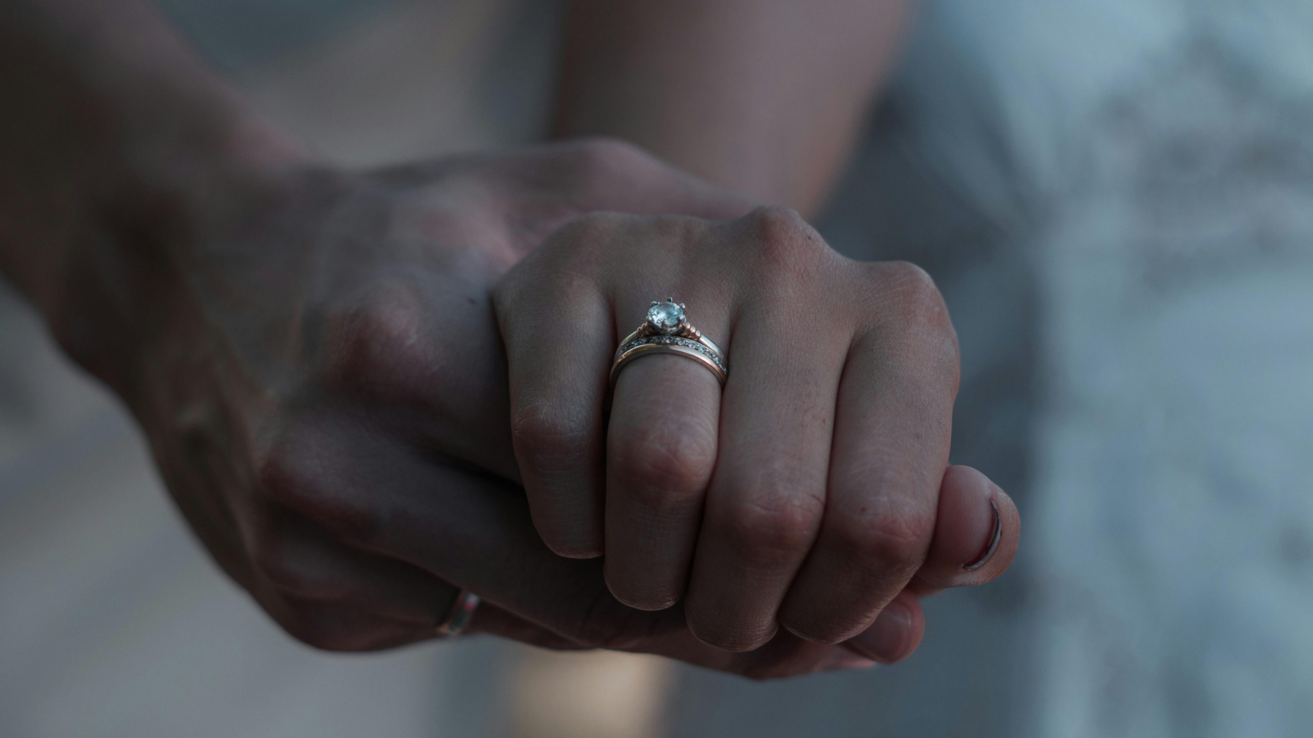 A romantic close-up of two hands holding elegantly with engagement rings, symbolizing love.