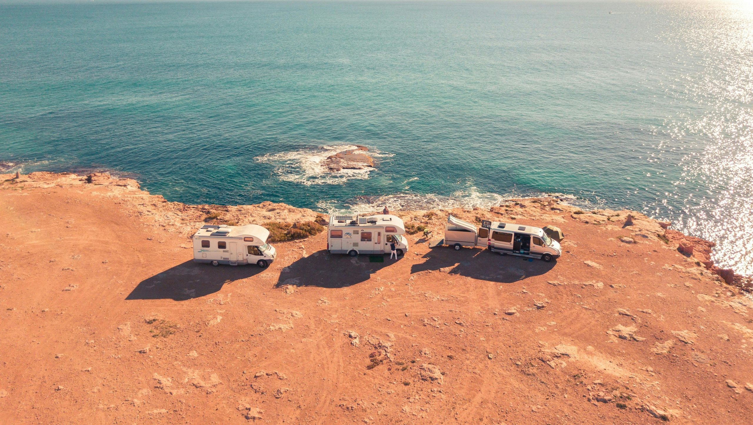 Three RVs parked on a scenic coastal cliff overlooking the ocean
