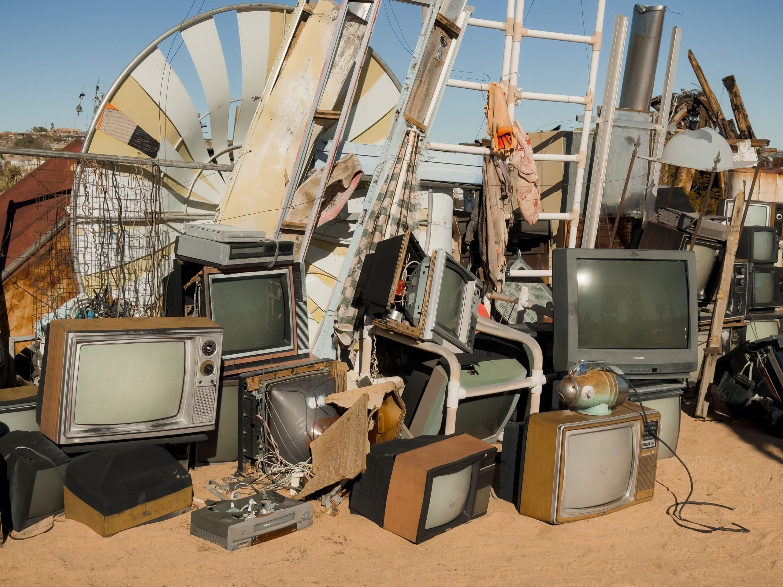 A pile of vintage televisions and scrap metal in the Joshua Tree desert