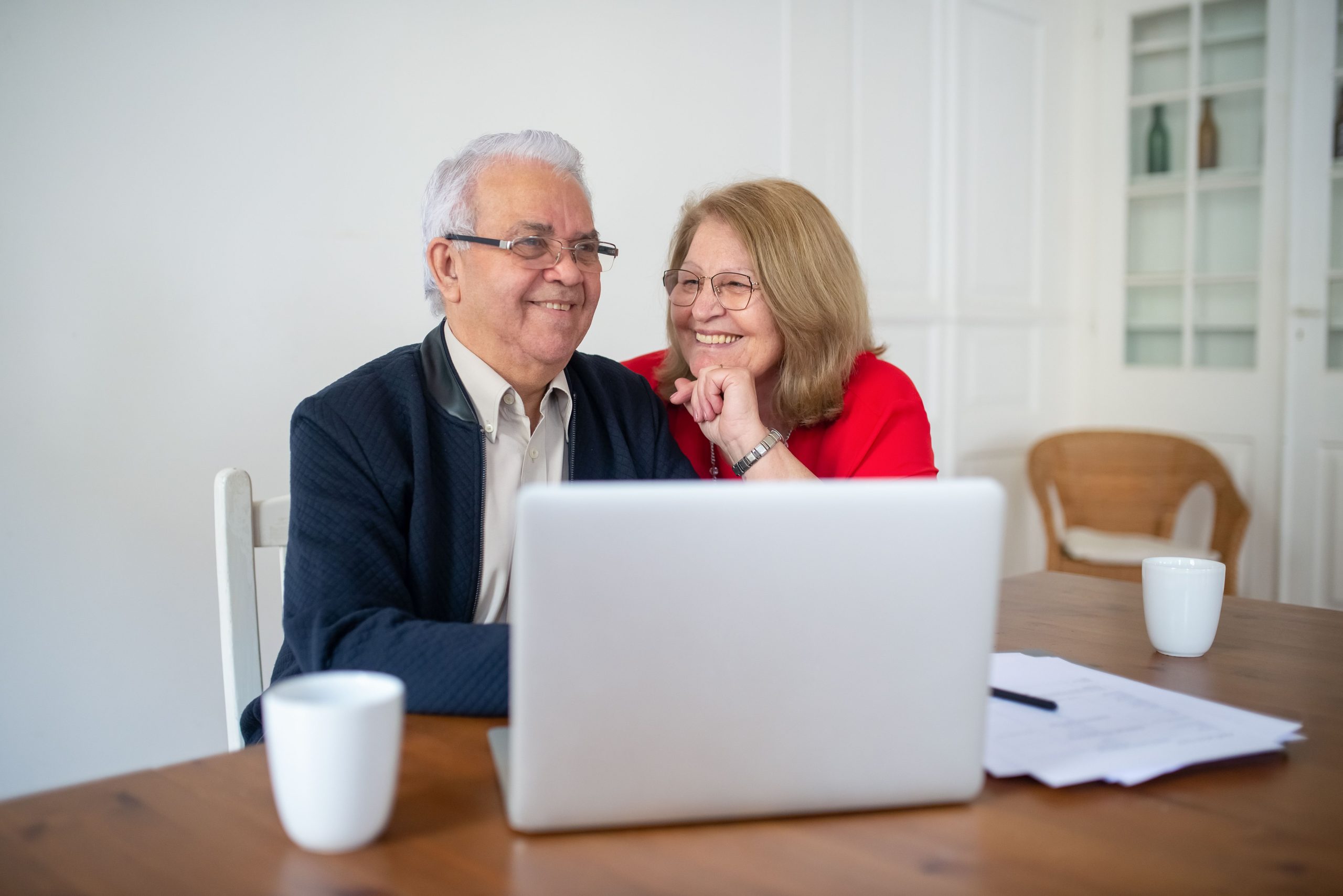 Senior couple smiling while using a laptop at home