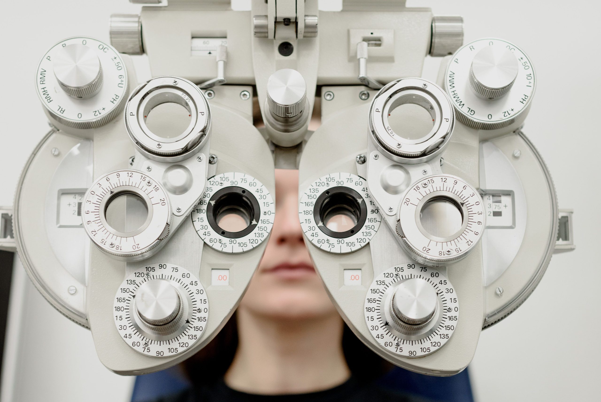 Woman undergoing eye examination using a phoropter in an optometry clinic