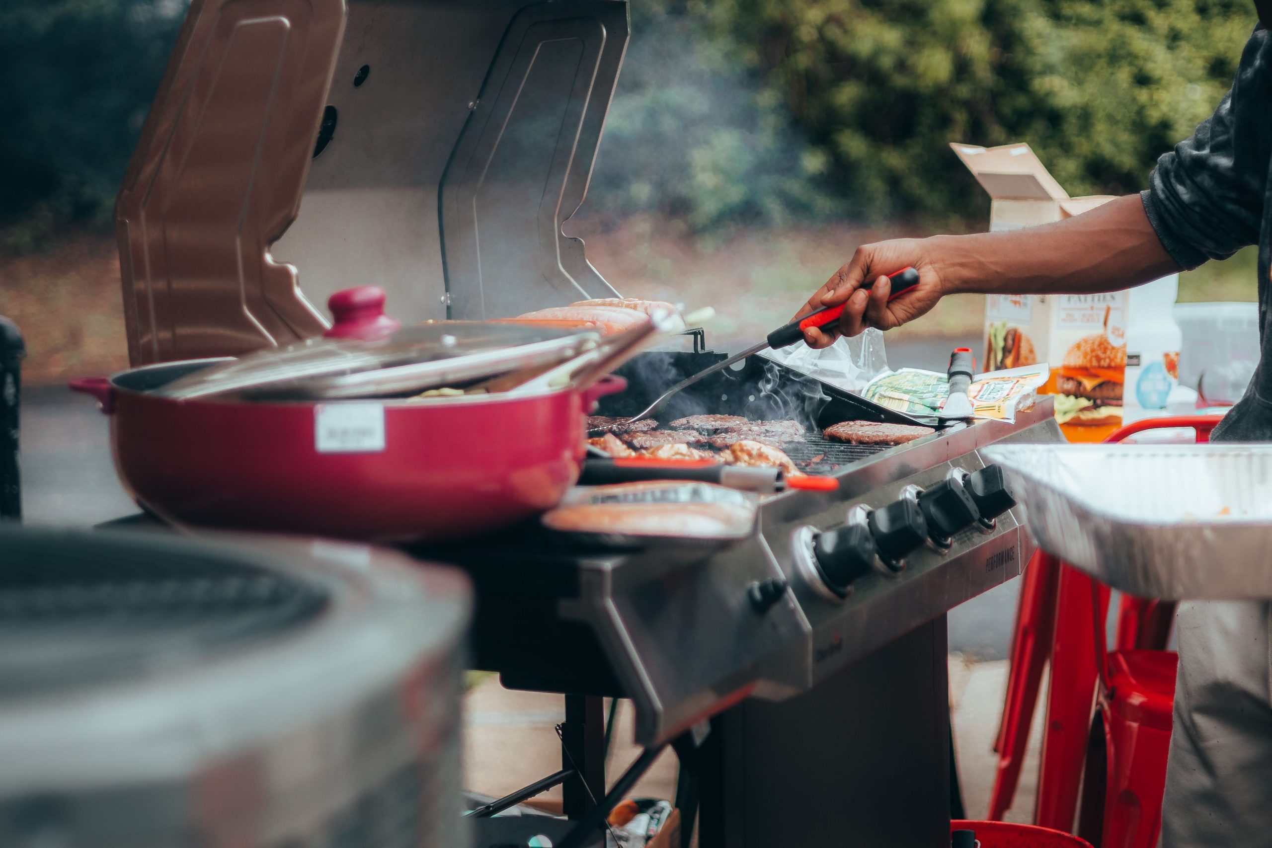 A close-up of grilling meats on a barbecue with visible smoke outdoors