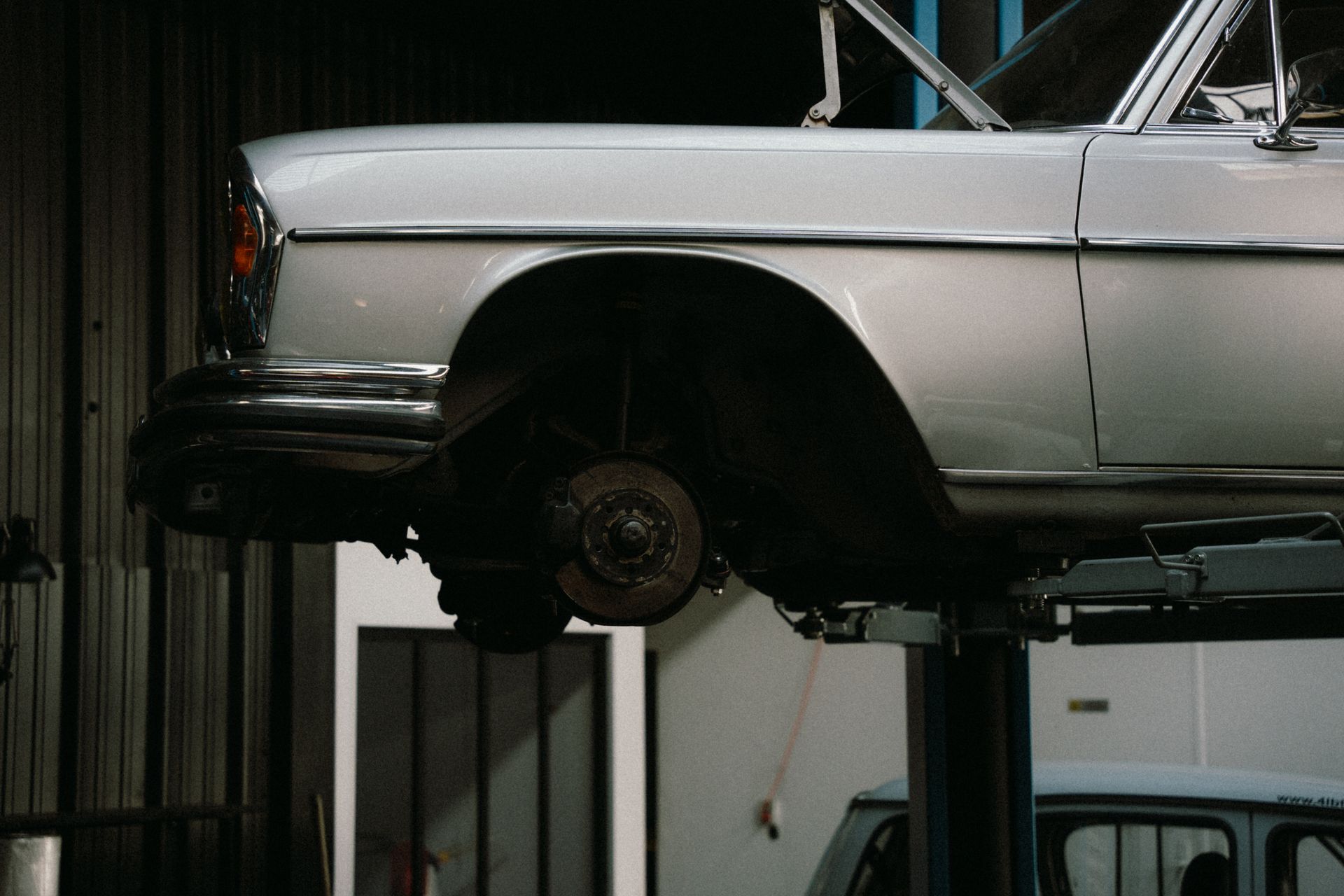 A classic car is elevated on a lift in a professional auto repair garage