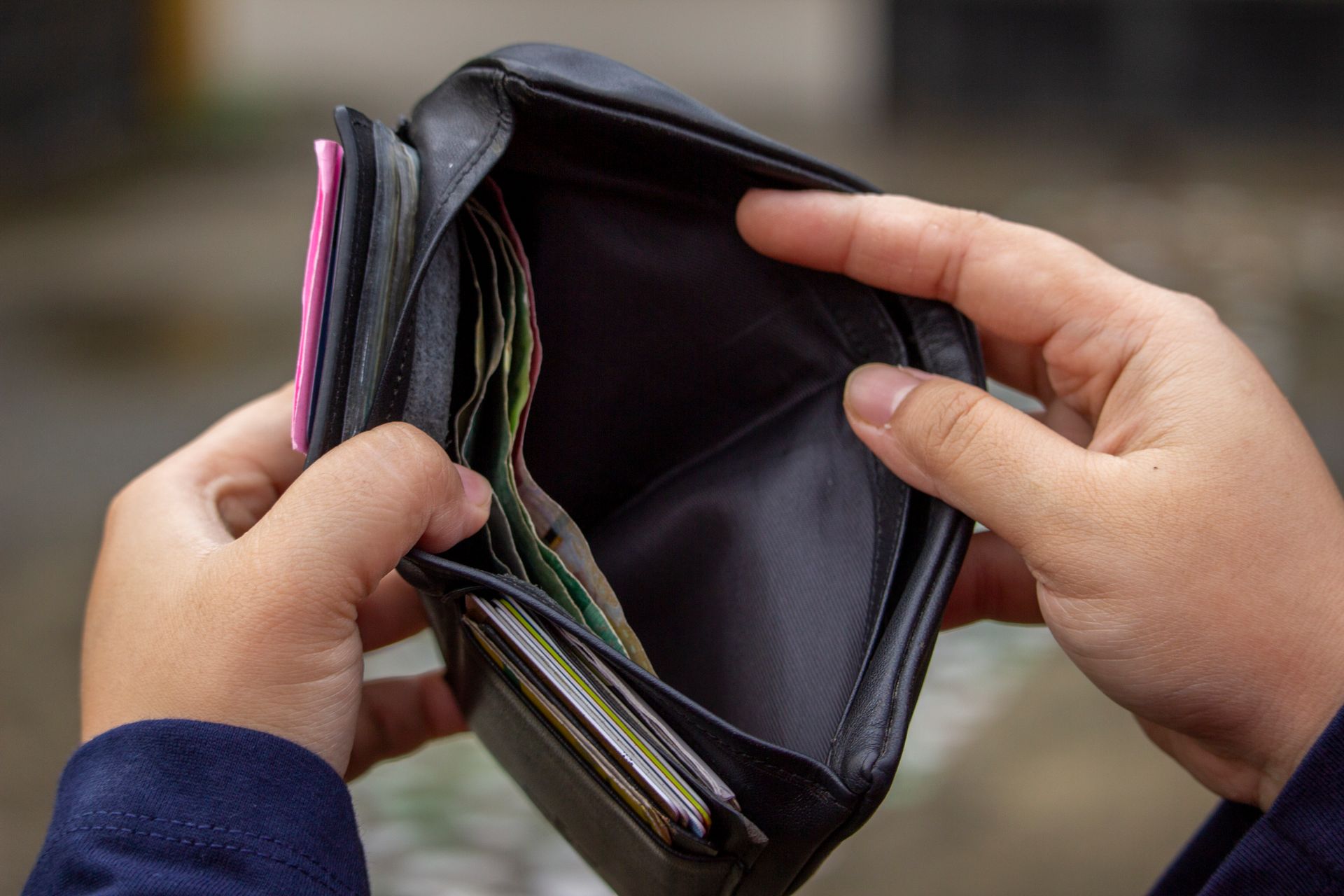 Hands holding an empty wallet, exploring themes of financial strain and budgeting.