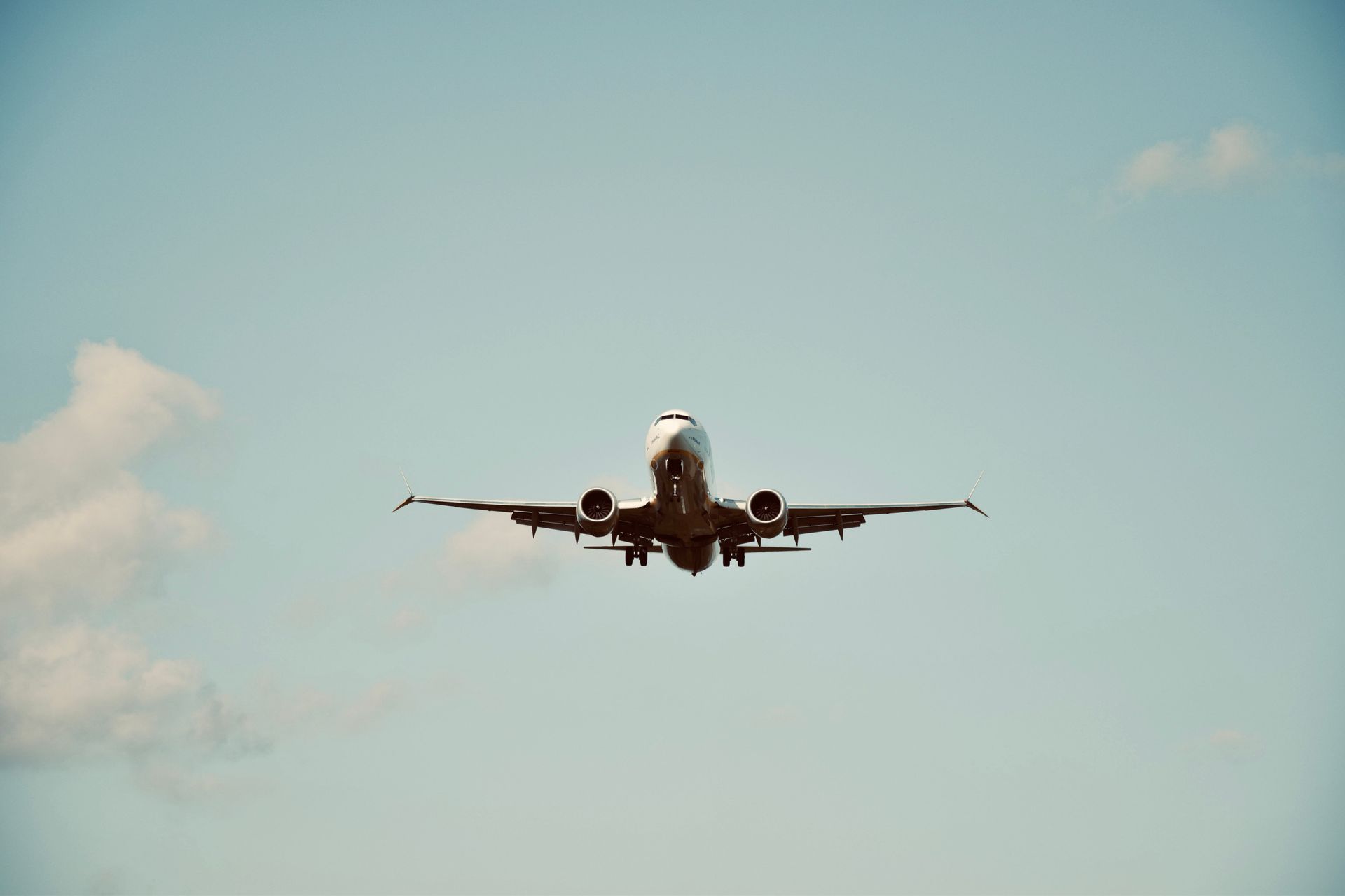 A commercial airplane in flight against a clear blue sky, representing air travel