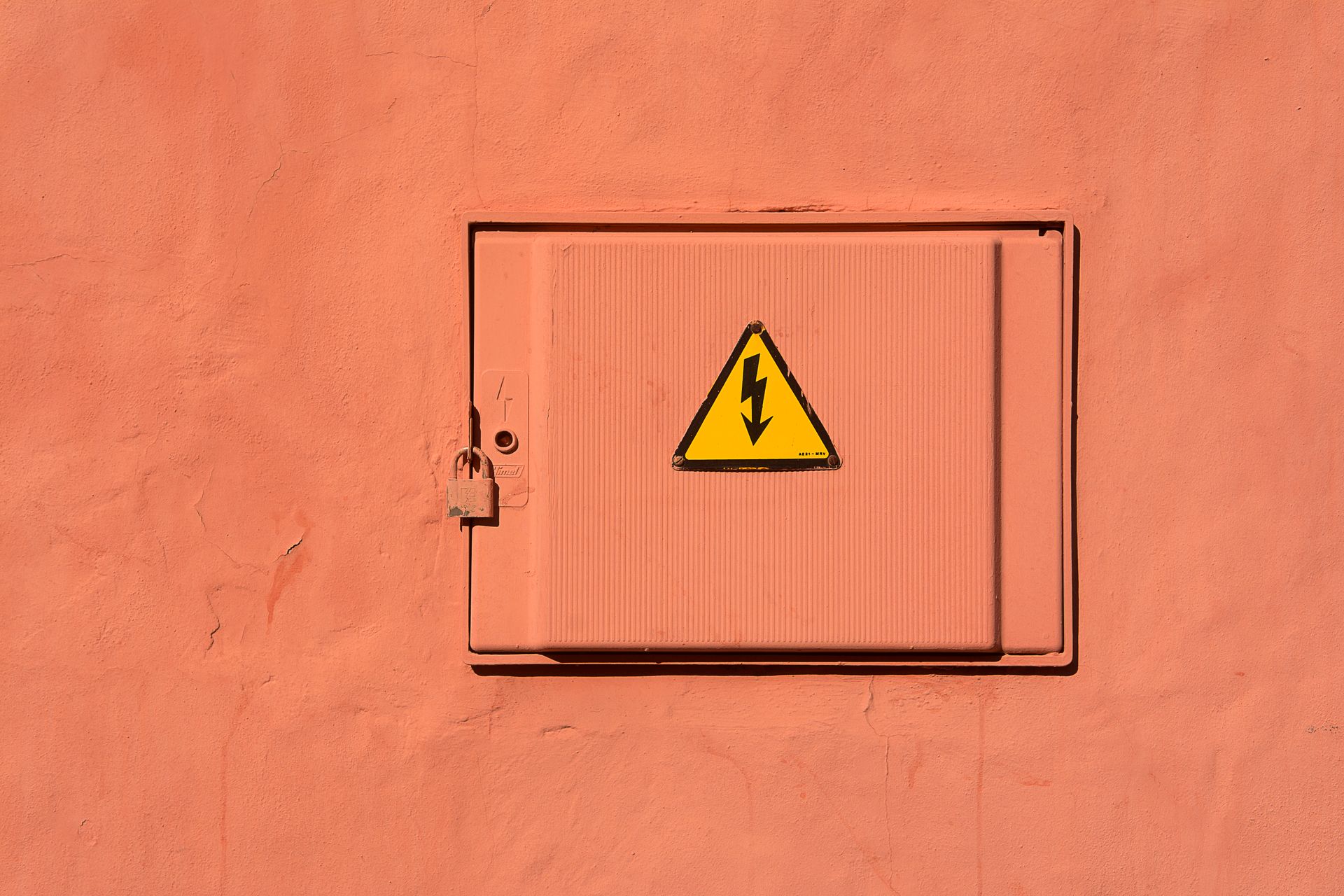 Bright yellow high voltage warning sign on a locked electrical box.